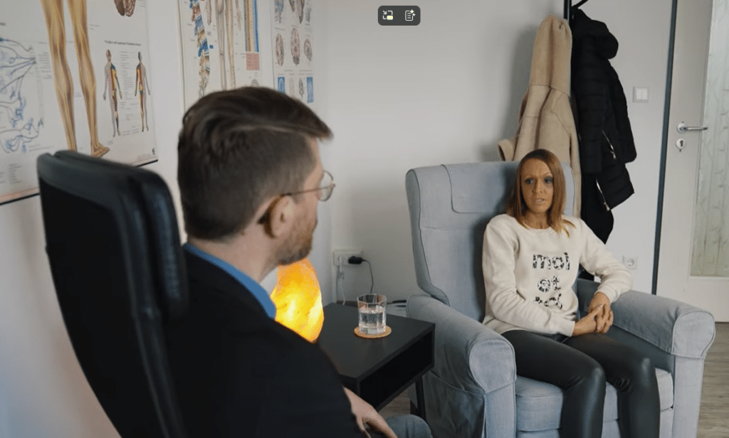 Empathischer Heilpraktiker für Psychotherapie sitzt lächelnd in seiner geschützten Praxis für Traumatherapie in Velbert.